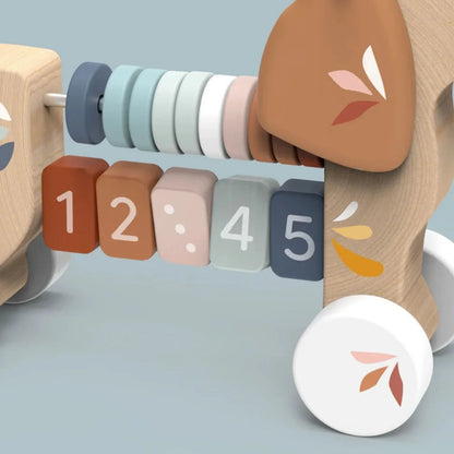 Close-up of the Speedy Monkey Puppy Pull Along abacus — numbered wooden blocks 1–5 in earthy terracotta, blush, sage, and slate tones. FSC certified, non-toxic baby toy by NARA.
