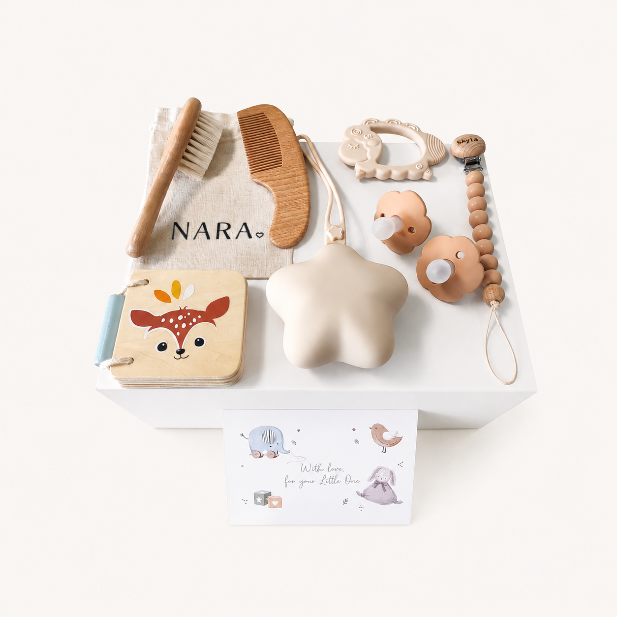 NARA × Speedy Monkey Personalised Petit Pamper & Care Gift Set — flatlay showing Speedy Monkey Forest book, beechwood hairbrush and comb in NARA cotton bag, silicone lamb teether, personalised dummy clip with beads, two pacifiers and star-shaped silicone case, styled in a white tray with a greeting card