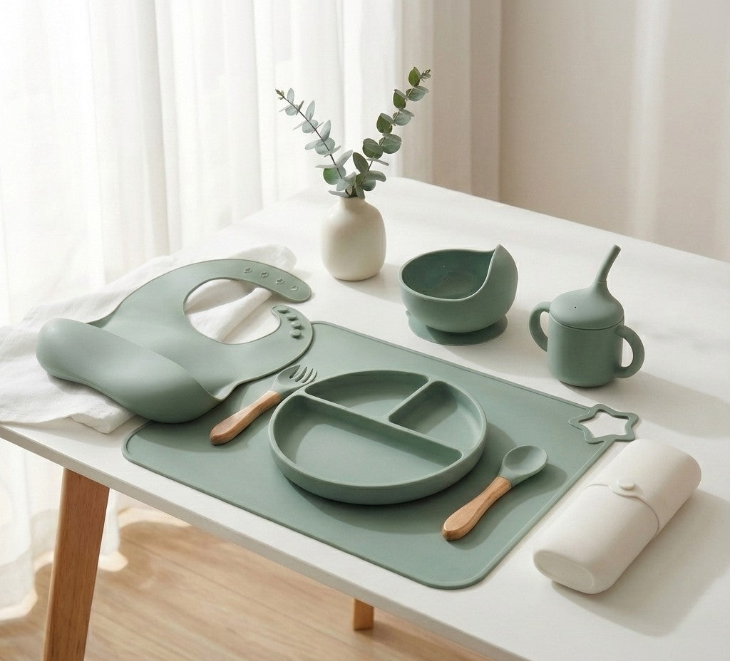 NARA Personalised Silicone Weaning Set in Sage Green — full 8-piece set laid out on a white table including suction plate, bowl, bib, training cup, placemat, cutlery case and wooden spoon and fork