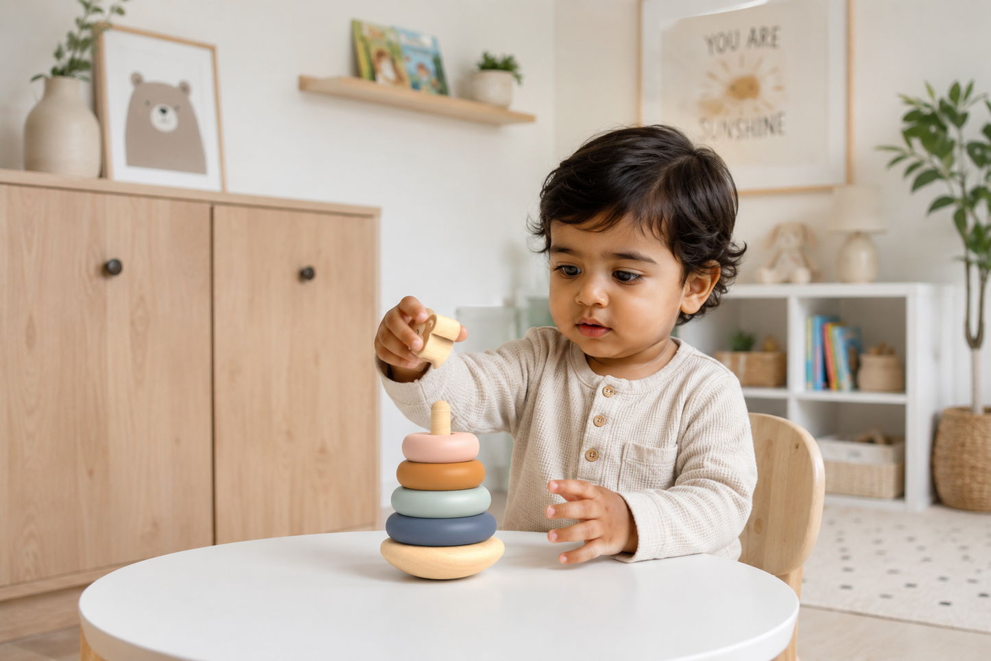 Toddler concentrating while stacking the Speedy Monkey Roly-Poly Stacker — pastel wooden ring stacking toy in a Scandi nursery, FSC certified baby toy by NARA
