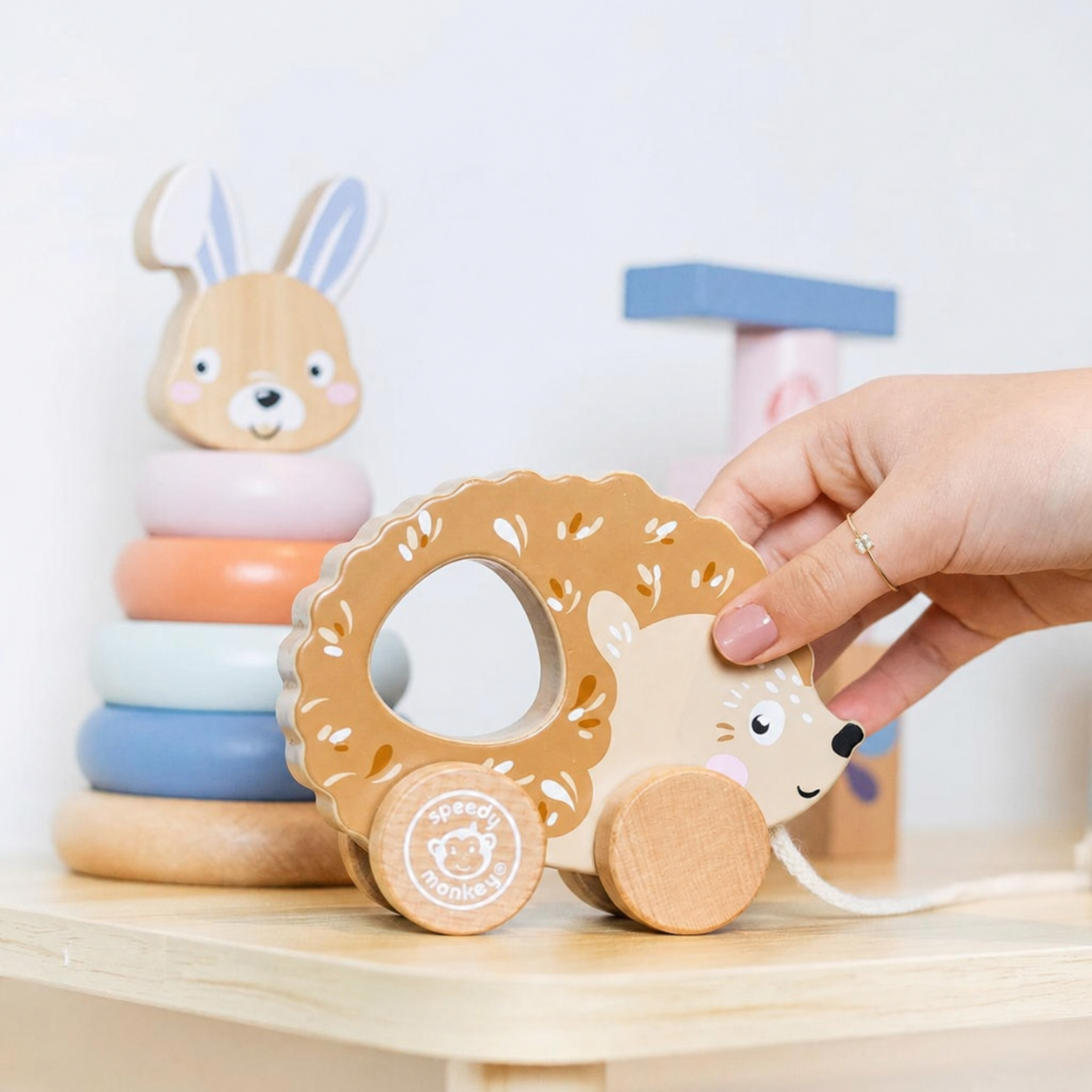 Speedy Monkey My First Toy Box — hand holding personalised pull-along hedgehog wooden toy, with stacking rabbit and building blocks in the background, FSC certified baby gift set by NARA